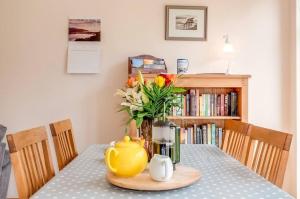 uma mesa com um bule de chá amarelo e flores sobre ele em Kinnen Cottage em Creetown