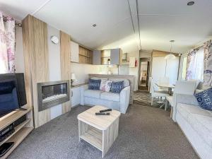 a living room with a couch and a tv at Modern Caravan With Decking At Azure Seas Along The Suffolk Coast Ref 32065az in Lowestoft