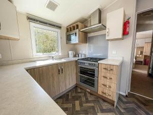 a kitchen with a stove and a sink at Modern Caravan With Decking At Azure Seas Along The Suffolk Coast Ref 32065az in Lowestoft