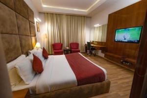 a hotel room with a bed and a flat screen tv at Hotel Millennium Inn, Prayagraj in Allahābād