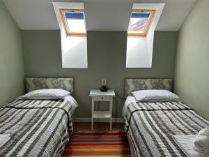 two beds in a room with two windows at The Wickerman Granary in Kirkcudbright