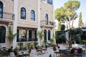 an outdoor patio with tables and chairs in front of a building at All Seasons Boutique Hotel - Jerusalem in Jerusalem