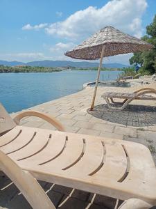 a wooden bench sitting next to a beach with an umbrella at ESKA 121 airport in Dalaman