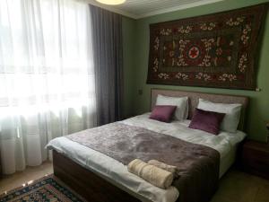 1 dormitorio con 1 cama grande con almohadas moradas en Guest House Ruh Achari en Sheki