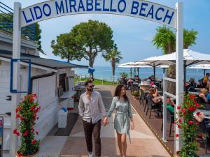 a man and a woman walking down a sidewalk under a sign at Parc Hotel Gritti in Bardolino