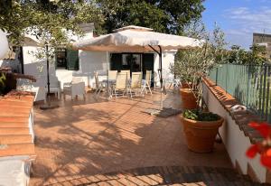 un patio con sombrilla, mesas y sillas en Villa Gina, en Marina di Fuscaldo