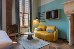 a living room with a yellow couch and a tv at Hotel St Joris I Kloeg Collection in Middelburg