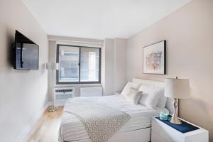 biała sypialnia z łóżkiem i oknem w obiekcie Gorgeous 2 BR in NYC with Elevator w Nowym Jorku