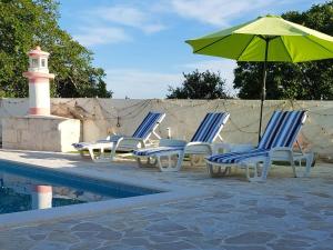 eine Gruppe Stühle und ein Sonnenschirm neben einem Pool in der Unterkunft Villa Roza 2 in Marina