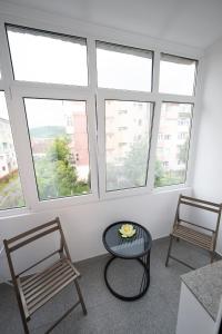 two chairs and a table in a room with windows at L&R Boutique Apartment in Oţelu Roşu