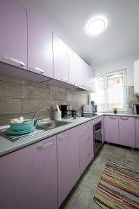 a kitchen with white cabinets and a sink at L&R Boutique Apartment in Oţelu Roşu