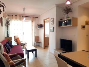 sala de estar con sofá y TV en AGUAMARINA, en Oropesa del Mar