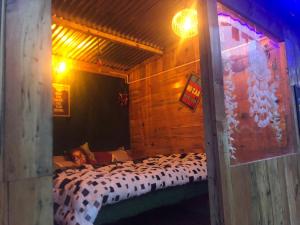 een persoon die in een bed in een houten kamer ligt bij Shanti People Huts & Camp in Kasol
