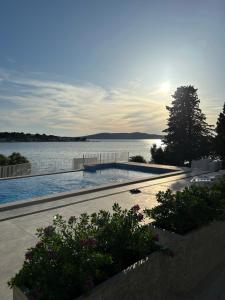 a swimming pool next to a large body of water at Apartments Jurić in Brodarica