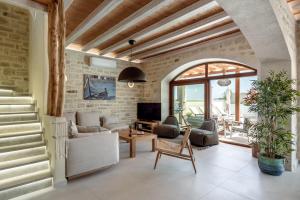 a living room with a stone wall at Pileas Villa, a Supreme Retreat by the Βeach, By ThinkVilla in Pigianos Kampos