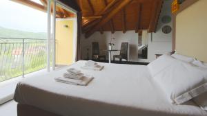 a bedroom with a white bed and a large window at Hotel Corte Santa Libera in San Fedele Intelvi