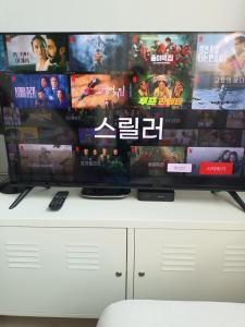 een flatscreen-tv op de top van een witte kast bij Blooming Guest House in Daegu