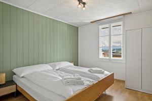 a bedroom with a bed with white sheets and a window at Erlen Rooms in Lucerne