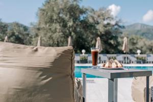 a table with a drink and a chair next to a pool at Pelithea Family Resort in Corfu