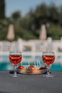 dwa kieliszki wina i talerz jedzenia na stole w obiekcie Pelithea Family Aparthotel by Hotelius w Korfu