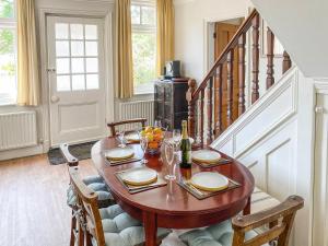 a dining room with a wooden table and a staircase at Framingham in South Hayling