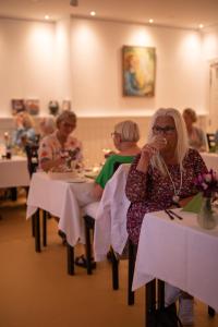 Skovsgård Hotel في Brovst: مجموعة من الناس يجلسون على الطاولات في المطعم