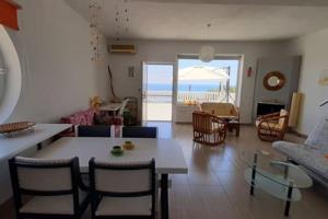 a living room with a table and chairs and the ocean at Marirena in Kali Limenes