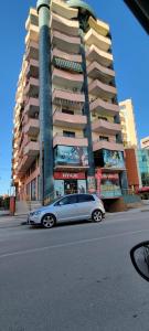 a silver car parked in front of a tall building at Charming Apartment Lushnje in Lushnjë