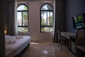 a hotel room with a bed and a desk and windows at All Seasons Boutique Hotel - Jerusalem in Jerusalem