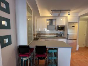 a kitchen with a counter and four stools at Balcón de la Torre del Morche en Torrox Costa in El Morche