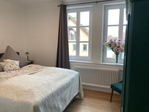 Un dormitorio con una cama y un jarrón de flores en una ventana en Ferienwohnung Grete, en Münsingen