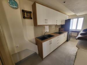 a kitchen with white cabinets and a sink and a clock at Sea & Relax Villa in Sarandë