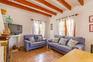 uma sala de estar com duas cadeiras azuis e uma televisão em Navarro em Pollença