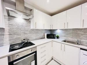a white kitchen with white cabinets and a sink at Battersea Studios by Sleepy in London