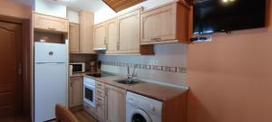 uma cozinha com armários de madeira e um frigorífico branco em Casa Cote em Torla