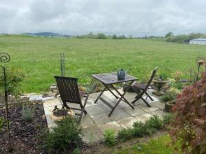 einen Tisch und Stühle auf einer Terrasse mit einem Feld in der Unterkunft Das blaue Haus - ein Sommertraum und ein Wintermärchen in Weiler-Simmerberg