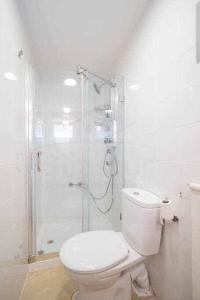 a white bathroom with a shower and a toilet at Árbol Blanco in Llanera