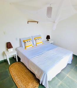 a white bedroom with a large bed with yellow pillows at The Spot - Beachfront Sports Pousada in Icaraí