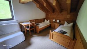 a bedroom with two beds and a desk and a table at Gasthof Starzelhaus in Mittelberg