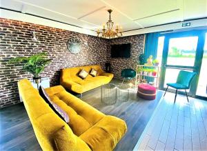 a living room with a yellow couch and a brick wall at Hôtel Restaurant Kyriad de Péronne in Péronne