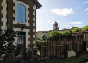 a house with a fence and a church in the background at Cute 1-bed cottage with view across park. in Issac