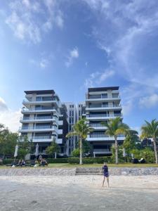 a person standing on the beach in front of a building at Hi Sea E272 At Escape Condominium Mae Pim Beach in Mae Pim