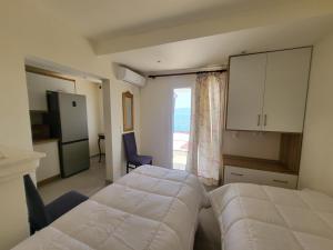 a bedroom with a bed and a kitchen with a window at Villa Sotiri in Sarandë