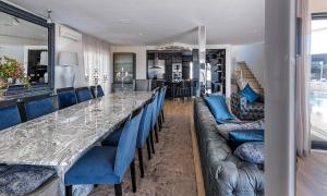 a dining room with a long table and blue chairs at Villa Legacy in Cape Town