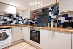 a kitchen with white cabinets and blue and white tiles at Modern, Sea Themed Ground Floor Flat Near Beach in New Quay