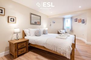 a bedroom with a bed with white sheets and a table at Modern, Sea Themed Ground Floor Flat Near Beach in New Quay