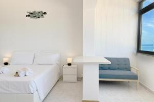ein weißes Schlafzimmer mit einem Bett und einem blauen Stuhl in der Unterkunft Studio on Alvor's Beach by amcf in Alvor