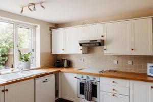 a kitchen with white cabinets and a sink and a window at Rodham House, Fenland Retreats at Willow Grange Farm in Cambridge