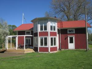 una pequeña casa roja con techo rojo y porche en Huldas Gård en Kumla