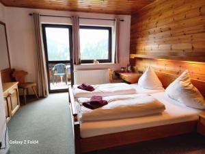two beds in a hotel room with a large window at Gasthof Starzelhaus in Mittelberg
